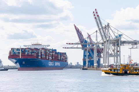 Ein Containerschiff von Cosco und Kräne am Hafen von Hamburg
