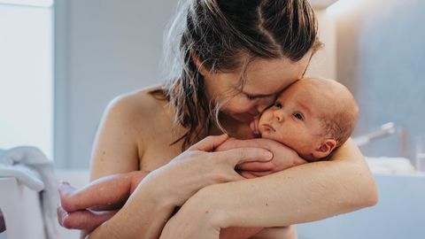 Eine Frau hält nach der Geburt ihr Neugeborenes im Arm