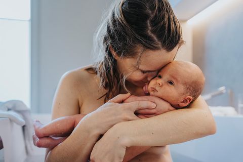 Eine Frau hält nach der Geburt ihr Neugeborenes im Arm