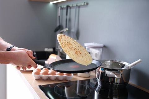 Ein Mann wendet einen Crepe in der Pfanne