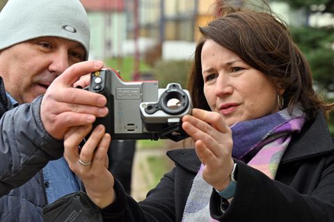 Ein Mann und eine Frau schauen auf einer Infrarot-Thermografiekamera nach den wärmsten Stellen einer Häuserfassade