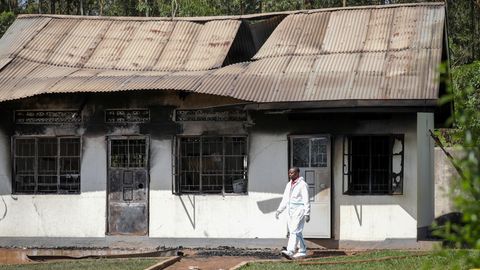 Ein Beamter der Spurensicherung geht an einem verbrannten Schulgebäude in Uganda vorbei