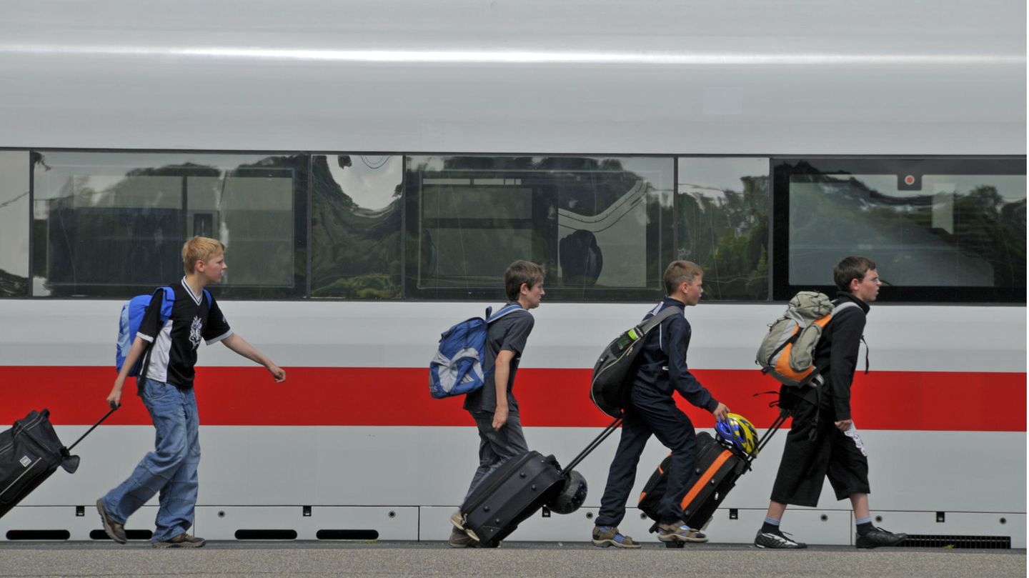 Kinder mit Koffern laufen am Bahnsteig