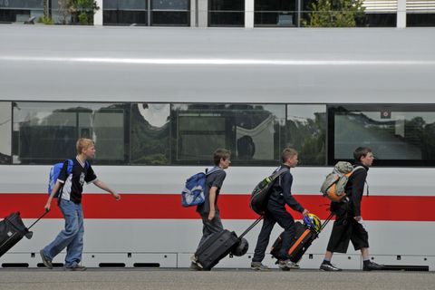 Kinder mit Koffern laufen am Bahnsteig