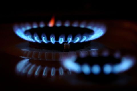 Aus den Düsen eines Gasherdes leuchten im Dunkeln blaue Flammen