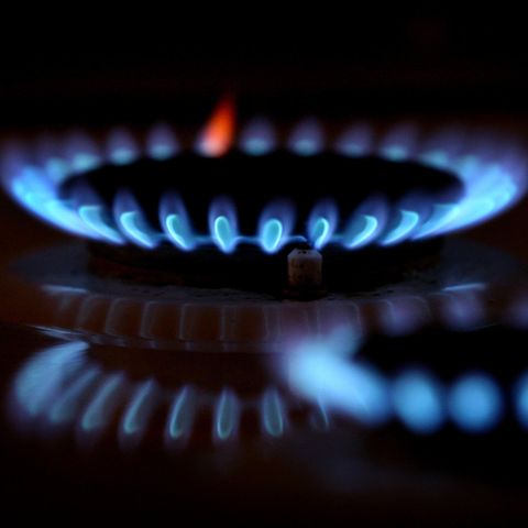 Aus den Düsen eines Gasherdes leuchten im Dunkeln blaue Flammen