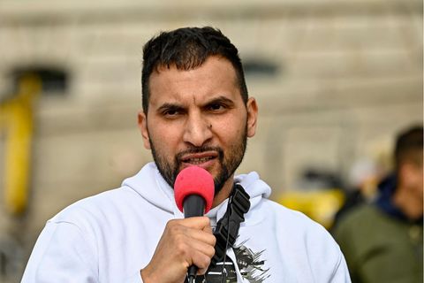 Ein dunkelhaariger junger Mann spricht offenbar wütend in ein Mikro mit rotem Windschutz