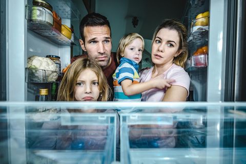 Eine Familie schaut traurig in einen leeren Kühlschrank