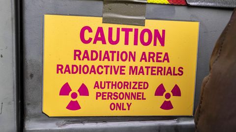 Ein rot-gelbes Schild mit der Aufschrift: "Caution. Radiation Area. Radioactive Materials. Authorized Personnel Only"
