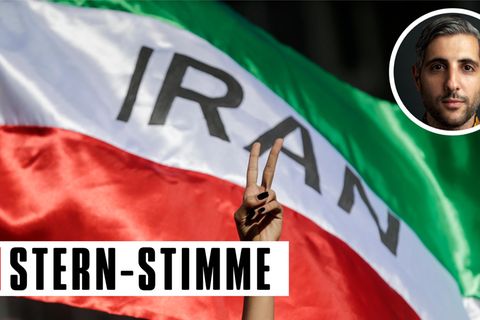 Eine Frau zeigt auf einer Demonstration für die Menschenrechte im Iran das Victory-Zeichen vor einer iranischen Fahne