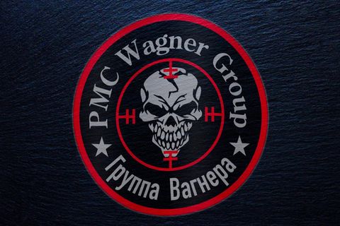 Ein rundes Logo zeigt in roter Umrandung einen grinsenden Totenschädel in einem Fadenkreuz unter der Schrift "PMC Wagner Group"