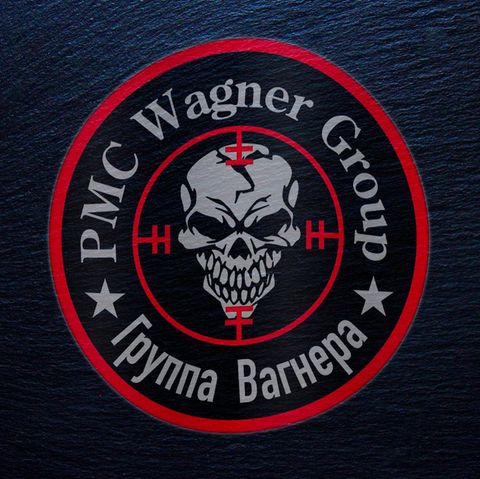 Ein rundes Logo zeigt in roter Umrandung einen grinsenden Totenschädel in einem Fadenkreuz unter der Schrift "PMC Wagner Group"