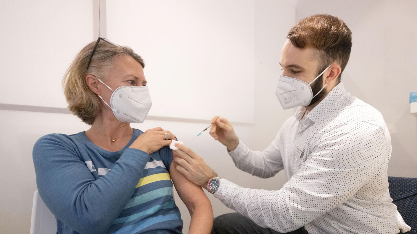Ein Mann mit weißem Hemd impft eine mittelalte Frau Ein Mann mit weißem Hemd impft eine mittelalte Frau