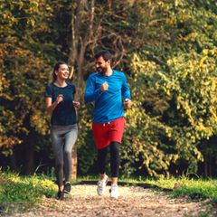 Laufen und Kompressionssocken: Eine Frau und ein Mann joggen durch einen Park
