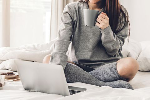 Chromebook vs. Laptop: Eine Frau sitzt mit Laptop auf der Couch