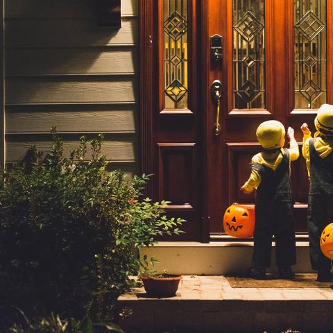 Zwei Kinder in Halloween-Kostümen klingeln an einer Haustür