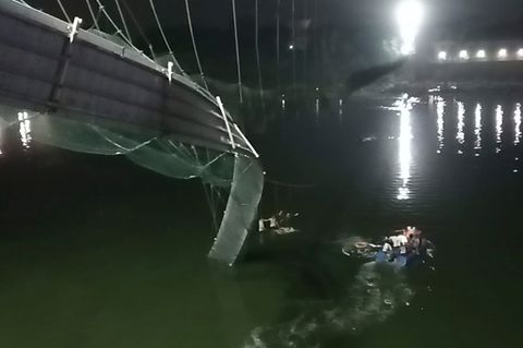 Rettungshelfer auf Booten suchen im Fluss Machchu neben einer eingestürzten Brücke nach Opfern