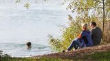 Frau schwimmt im Oktober in Badesee