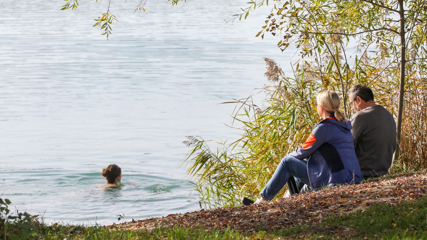 Frau schwimmt im Oktober in Badesee