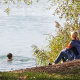 Frau schwimmt im Oktober in Badesee
