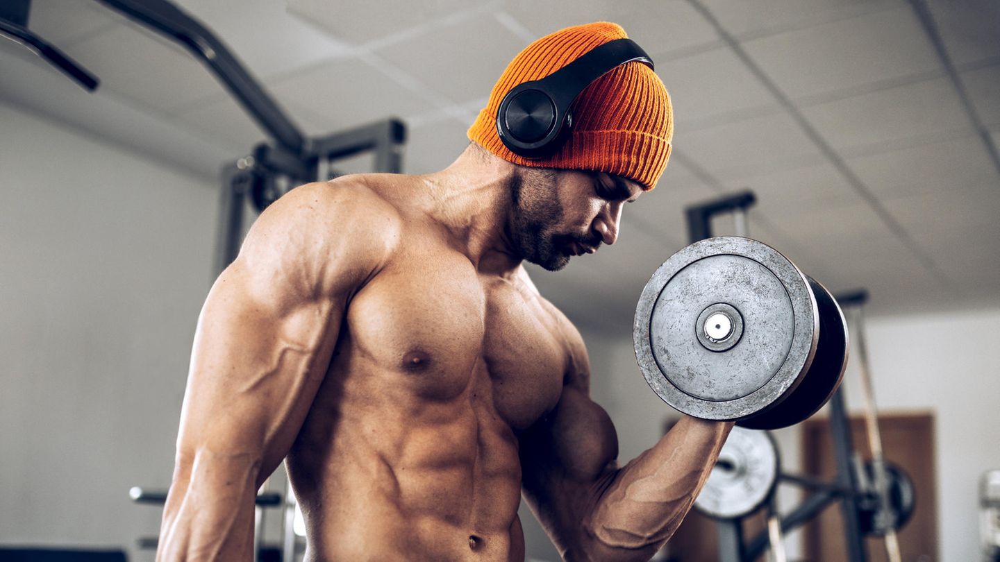 Ein Mann stemmt im Fitnessstudio Gewichte. Ein Mann stemmt im Fitnessstudio Gewichte.