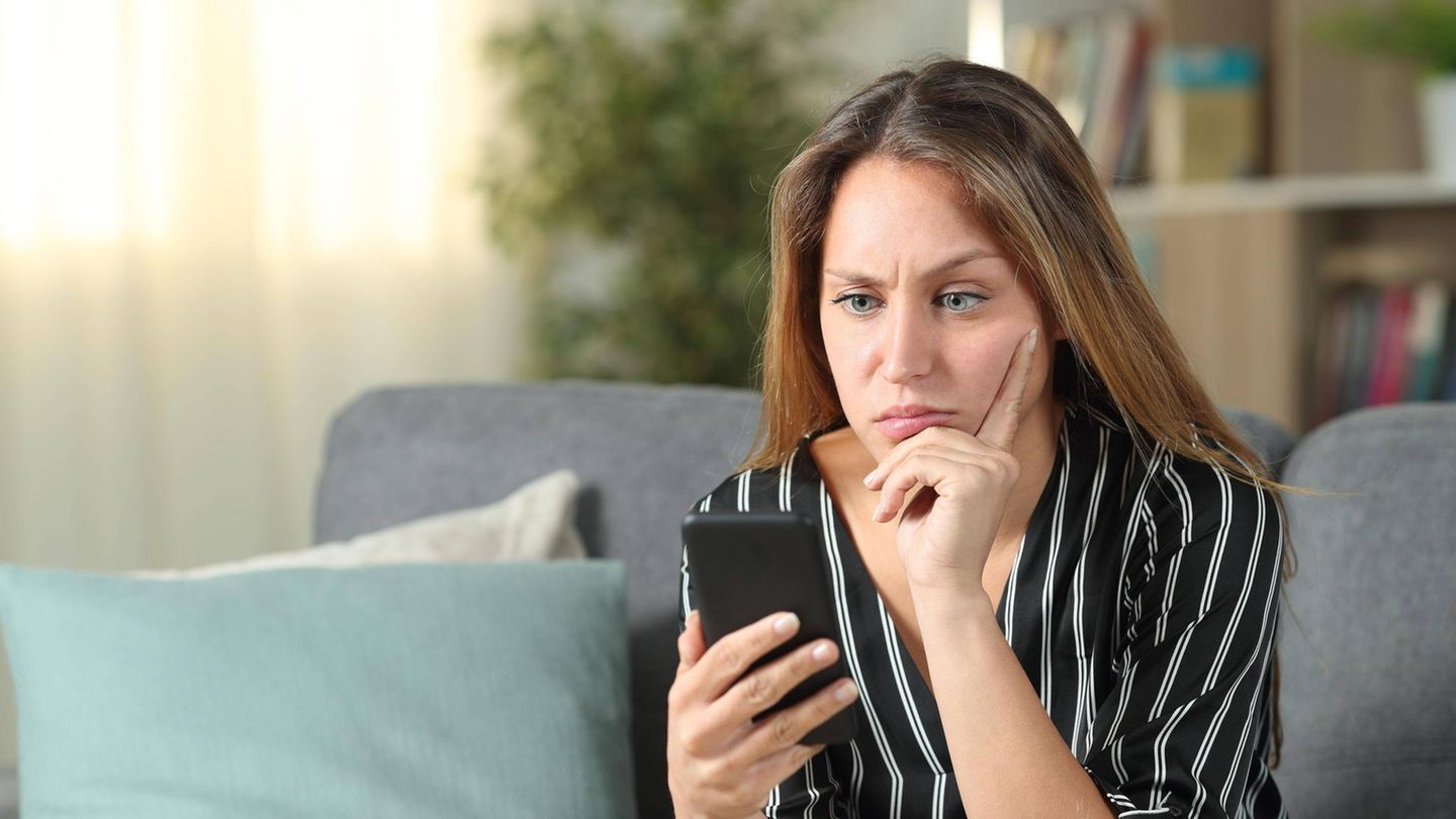 Eine Frau schaut genervt auf ihr Smartphone. Eine Frau schaut genervt auf ihr Smartphone.