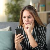 Eine Frau schaut genervt auf ihr Smartphone.