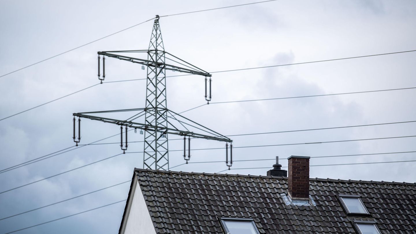 Ein Strommast steht hinter einem Wohnhaus