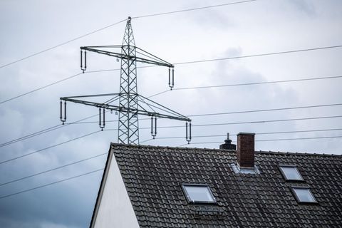 Ein Strommast steht hinter einem Wohnhaus