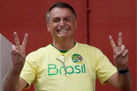 Ein braungebrannter älterer Mann im gelben "Brasil"-T-Shirt macht mit beiden Händen Victory-Zeichen und lächelt breit