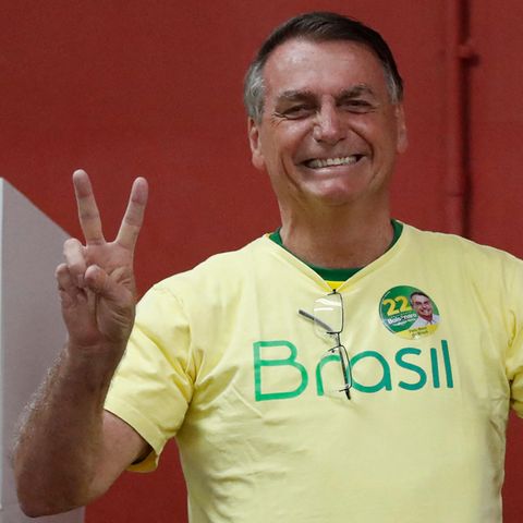 Ein braungebrannter älterer Mann im gelben "Brasil"-T-Shirt macht mit beiden Händen Victory-Zeichen und lächelt breit
