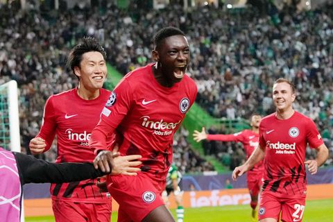 Ein schwarzer, ein asiatischer und ein weißer Fußballprofi in roten Trikots bejubeln gemeinsam ein Tor