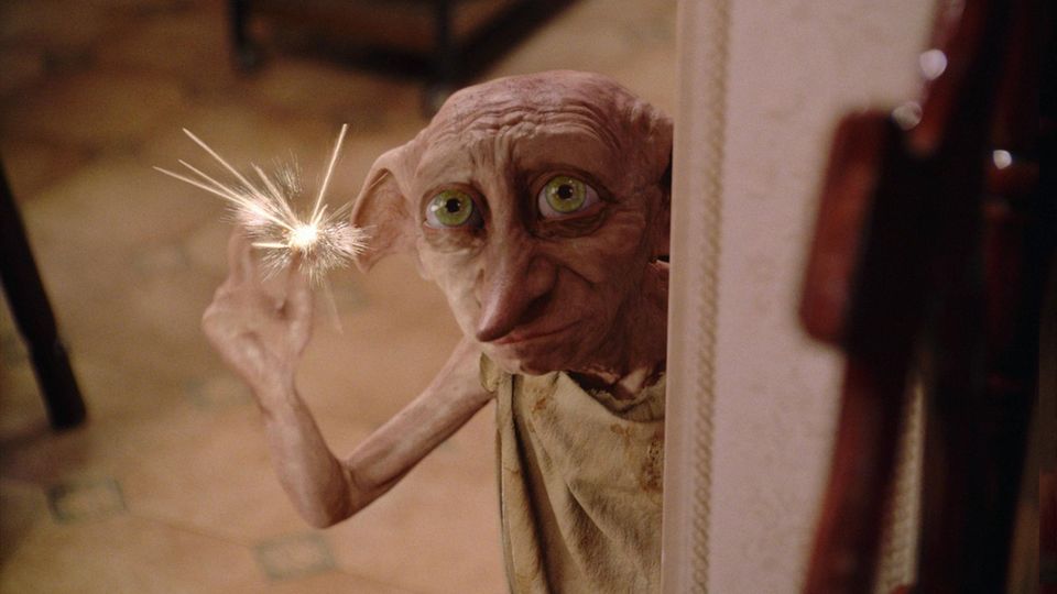 Hauself Dobby aus dem Harry Potter-Universum hält eine Art Wunderkerze in der Hand