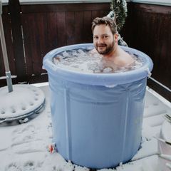 Regeneration nach dem Sport: Ein Mann sitzt in einer Plastikwanne mit Eiswasser