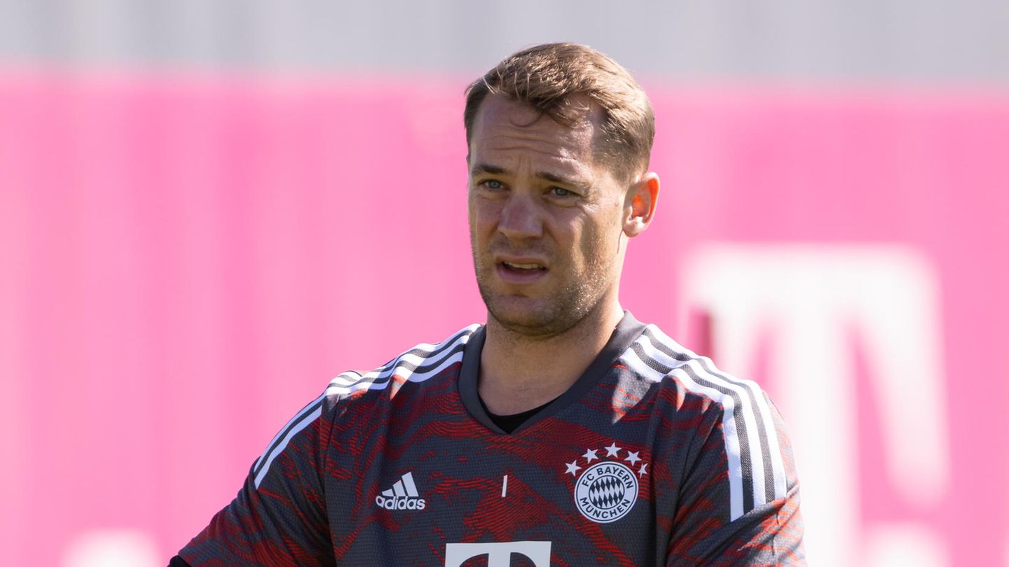 Ein weißer junger Mann mit blondem Seitenscheitel steht im dunkelblau-rot gemusterten Torwart-Dress auf einem Trainingsplatz