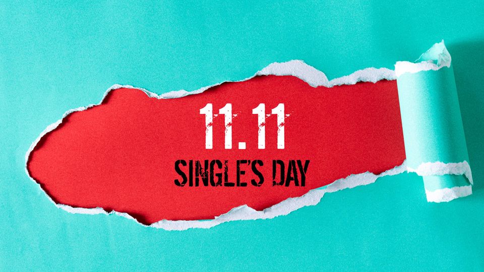 Ein Schild mit der Aufschrift "Singles Day 11.11." und weiterer Deko liegt auf rotem Untergrund