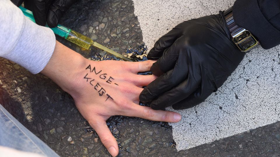 Umweltaktivisten kleben sich an Fahrbahn fest