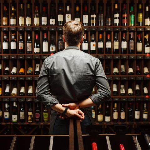 Mann steht vor Weinregal