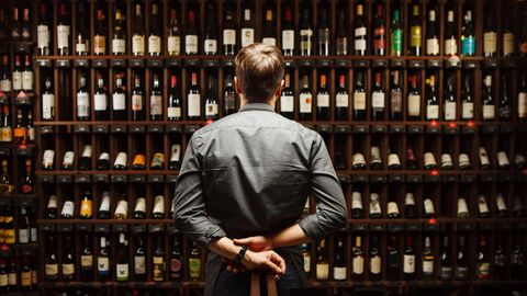Mann steht vor Weinregal