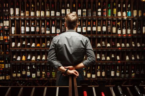 Mann steht vor Weinregal