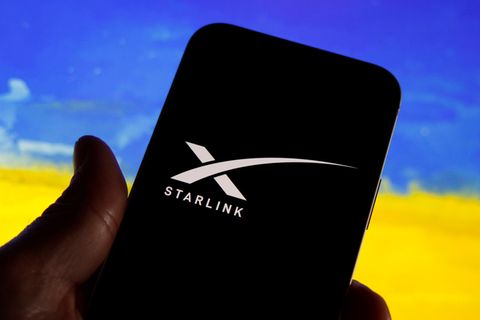 Ein Smartphone mit Starlink-Logo, dahinter die Fahne der Ukraine