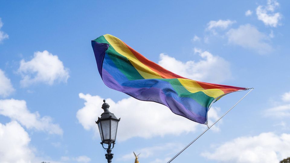Regenbogen-Flagge vor einem bewölkten Himmel