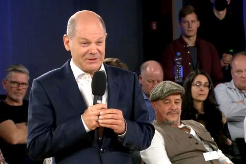 Bundeskanzler Olaf Scholz scheint mit einem Lachen zu reagieren.
