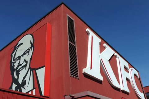 Das Logo der Fastfoodkette Kentucky Fried Chicken (KFC) vor einer Filiale des Unternehmens in München
