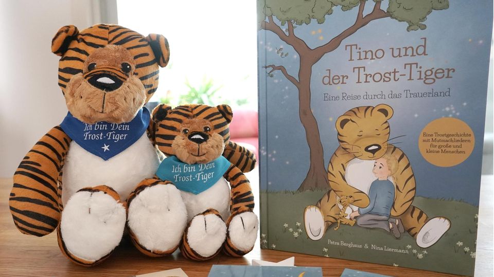 Zwei Stoff-Tiger sitzen neben einem aufgestellten Kinderbuch