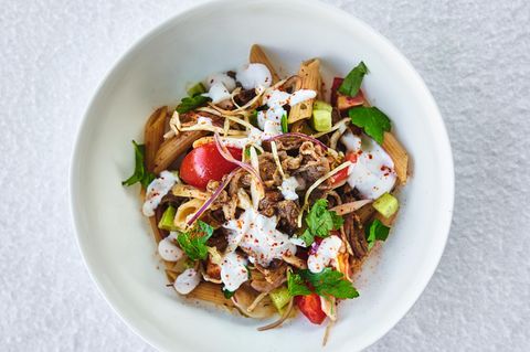 Döner-Pasta          LAMMHÜFTE 400 g LammhüfteKreuzkümmelRaz el HanoutIsotPiment d’EspeletteGaram MasalaSalzfrisch gemahlener schwarzer Pfefferetwas Olivenöl      GEMÜSE 50 g Kirschtomatenetwas OlivenölFenchelsaatBockshornkleeSternanisfrisch gemahlener schwarzer Pfefferetwas weißer Balsamicoessig1 GurkeSalz200 g Blaukraut1 rote Zwiebel30 g Blattpetersilie      JOGHURTSAUCE 150 g JoghurtSalzfrisch gemahlener schwarzer PfefferSaft von 1 ZitronePiment d’Espelette  PASTA       • 600 g Vollkornpasta (Fusilli oder Penne)      ZUM ANRICHTEN       • Salz  • Chiliflocken      LAMMHÜFTE   Die Lammhüfte in einer Mischung aus Kreuzkümmel, Raz el Hanout, Isot, Piment d’Espelette, Garam Masala, Salz und Pfeffer ca. 24 Stunden lang marinieren und anschließend die Lammhüfte einfrieren. Wenn die Hüfte komplett durchgefroren ist, mithilfe einer Aufschnittmaschine ganz dünn aufschneiden. Dann die fein geschnittene Lammhüfte in einer Pfanne mit wenig Olivenöl oder auf einer Grillplatte kurz scharf anbraten und auf einem Lochgitter abtropfen lassen.      GEMÜSE   Die Kirschtomaten in Olivenöl zusammen mit Fenchelsaat, Bockshornklee, Sternanis und schwarzem Pfeffer scharf anbraten, anschließend mit weißem Essig ablöschen und kurz einreduzieren lassen. Die Kirschtomaten dann im Sud abkühlen lassen und ebenfalls 24 Stunden lang im Sud liegen lassen.  Die Gurken schälen, das Kerngehäuse entfernen und leicht salzen.  Das Blaukraut in feine Julienne-Streifen schneiden, diese leicht salzen und mit weißem Essig marinieren.  Die rote Zwiebel schälen und in feine Streifen schneiden, anschließend für ca. 15 Minuten in kaltes Wasser einlegen.  Die Blattpetersilie gut waschen, abtropfen lassen und dann grob hacken.      JOGHURTSAUCE   Den Joghurt aufrühren und mit Salz, Pfeffer, Zitronensaft und Piment d’Espelette abschmecken.      PASTA   Die Nudeln al dente kochen.      ANRICHTEN   Die Nudeln zusammen mit der Lammhüfte und dem Gemüse durchschwenken und gegebenenfalls nochmals mit etwas Salz abschmecken. Die fertige Pasta dann mit der Joghurtsauce beträufeln, die grob gehackte Petersilie darüber verteilen und nach eigenem Geschmack scharf mit Chiliflocken abschmecken.