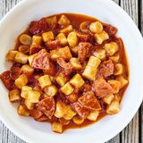 Sucuk-Pasta      PASTA  • 200 g Mehl (Type 405) + etwas mehr zum Bestäuben  • lauwarmes Wasser  • etwas Olivenöl  • 200 g Paniermehl  • Salz      TOMATENSAUCE  • 2 Zwiebeln  • 1⁄2 kleine rote Chili-  schote  • 1 Knoblauchzehe  • etwas Olivenöl  • 15 g grob gemahlener schwarzer  Pfeffer  • 400 g Dosentomaten      SUCUK  • 300 g Sucuk  • etwas Olivenöl  • 100 g Kirschtomaten  • Tomatensauce  (siehe Teilrezept)  • Salz  • Kreuzkümmel      ZUM ANRICHTEN  • nach Belieben frisches Basilikum      PASTA  Das Mehl mit lauwarmem Wasser und 1 Spritzer Olivenöl langsam verkneten, bis eine homogene, nicht zu feuchte Masse entsteht.  Das Paniermehl ebenfalls mit etwas lauwarmem Wasser und 1 Schuss Olivenöl zu einer klumpigen Masse verkneten.  Beide Teige dann zusammen mithilfe einer Küchenmaschine vermengen und etwas Salz hinzugeben. Den Teig nun für ca. 1 Stunde abgedeckt im Kühlschrank ruhen lassen.  Anschließend den Teig in ca. 1 cm dicke Scheiben schneiden, die Scheiben dann in gleich große Streifen schneiden, diese mit etwas Mehl bestäuben, um das Verkleben zu verhindern, und mit den Händen anschließend rund ausrollen. Die Streifen in ca. 1 cm dicke Stücke schneiden und in Salzwasser ca. 12 Minuten kochen.      TOMATENSAUCE  Die Zwiebeln, die Chili und den Knoblauch in feine Würfel schneiden. Zusammen in Olivenöl bei milder Hitze leicht anschwitzen und den grob gemahlenen Pfeffer hinzugeben. Dann die Dosentomaten dazugeben und alles zusammen ca. 1 Stunde leise köcheln lassen.      SUCUK  Die Sucuk von der Haut befreien und in möglichst gleich große, ca. 1 cm große Würfel schneiden. Die Würfel in ein wenig Olivenöl knusprig ausbraten, zum Schluss geviertelte Kirschtomaten und die Tomatensauce hinzugeben und das Ganze nun nochmals für ca. 10–15 Minuten leise köcheln lassen. Mit Salz und Kreuzkümmel abschmecken.      ANRICHTEN  Die Pasta zusammen mit der Sauce erhitzen und gegebenenfalls mit frischem Basilikum ausgarnieren.