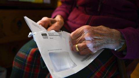 Eine Rentnerin öffnet einen Brief der Deutschen Rentenversicherung