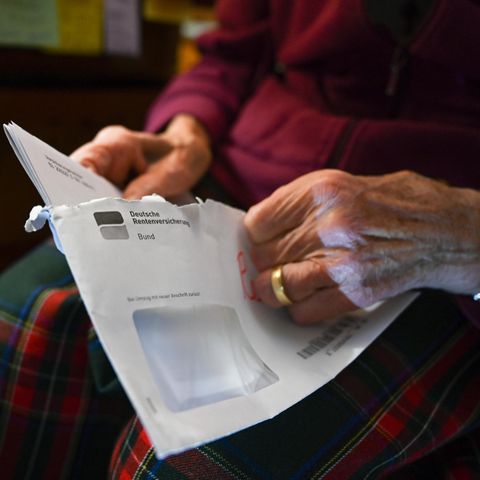 Eine Rentnerin öffnet einen Brief der Deutschen Rentenversicherung