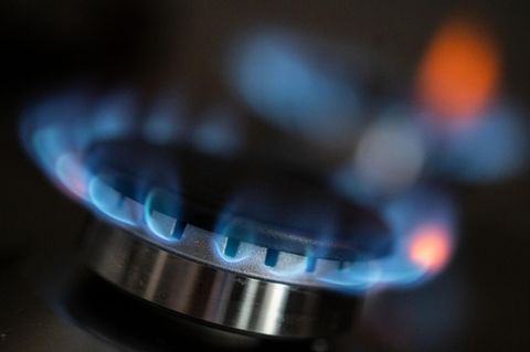 Auf einem Gasherd kommen blaue Flammen aus dem Brenner